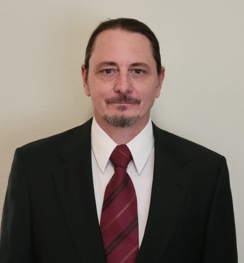 A man in a suit and tie standing up against a wall.