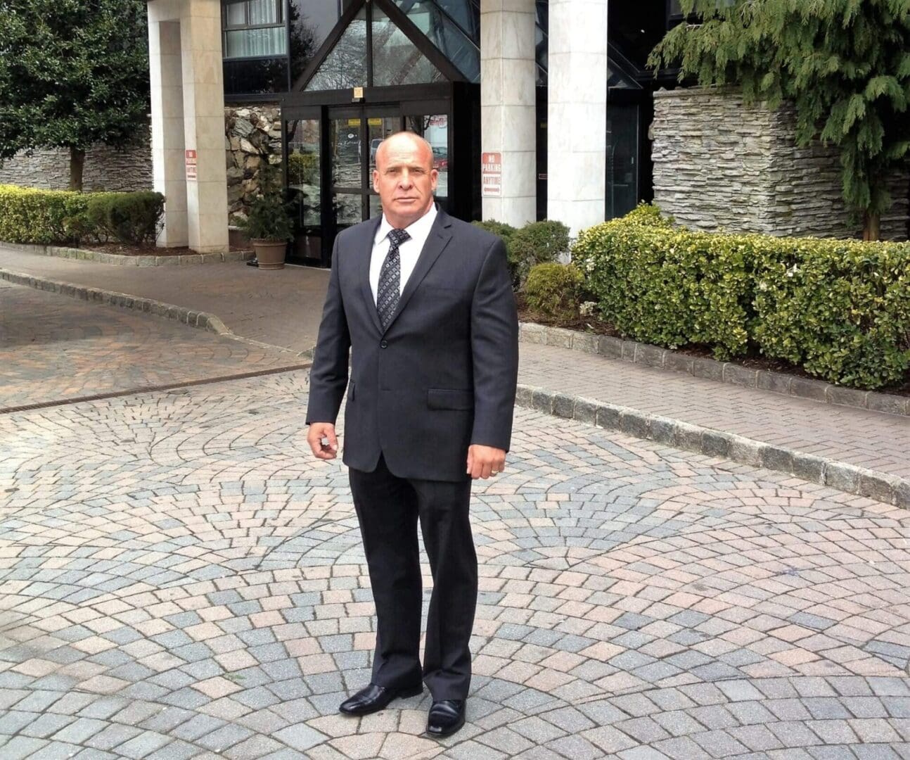 A man in a suit and tie standing on the sidewalk.