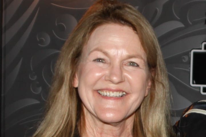 A woman with long hair smiles for the camera.