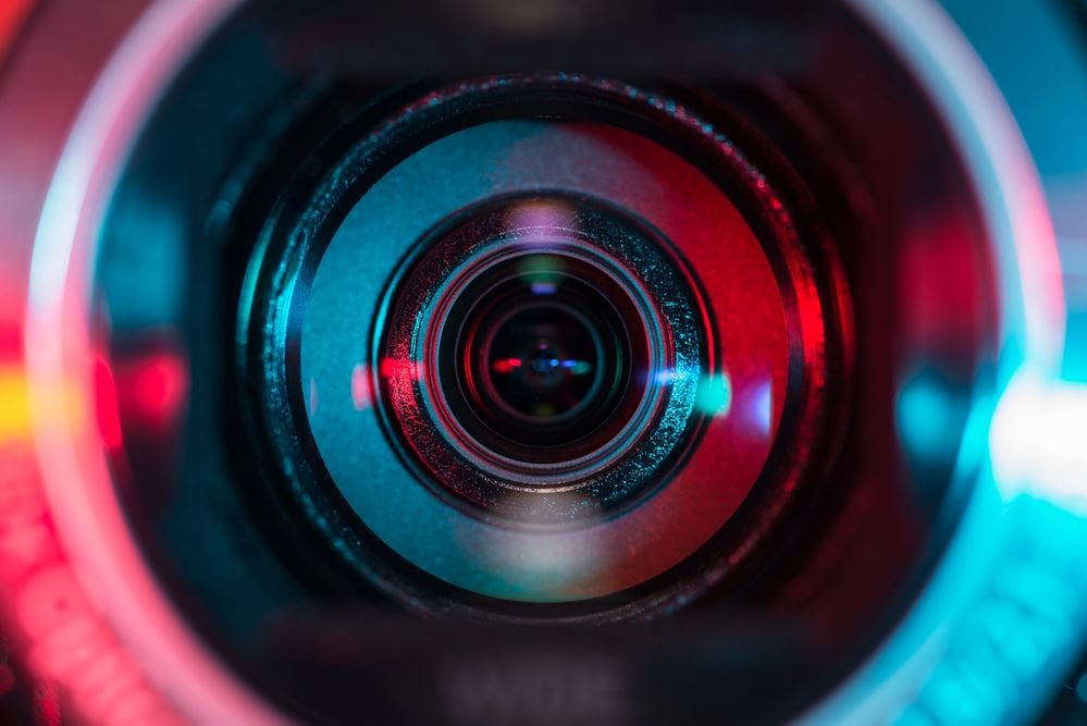 A camera lens with red and blue reflections.