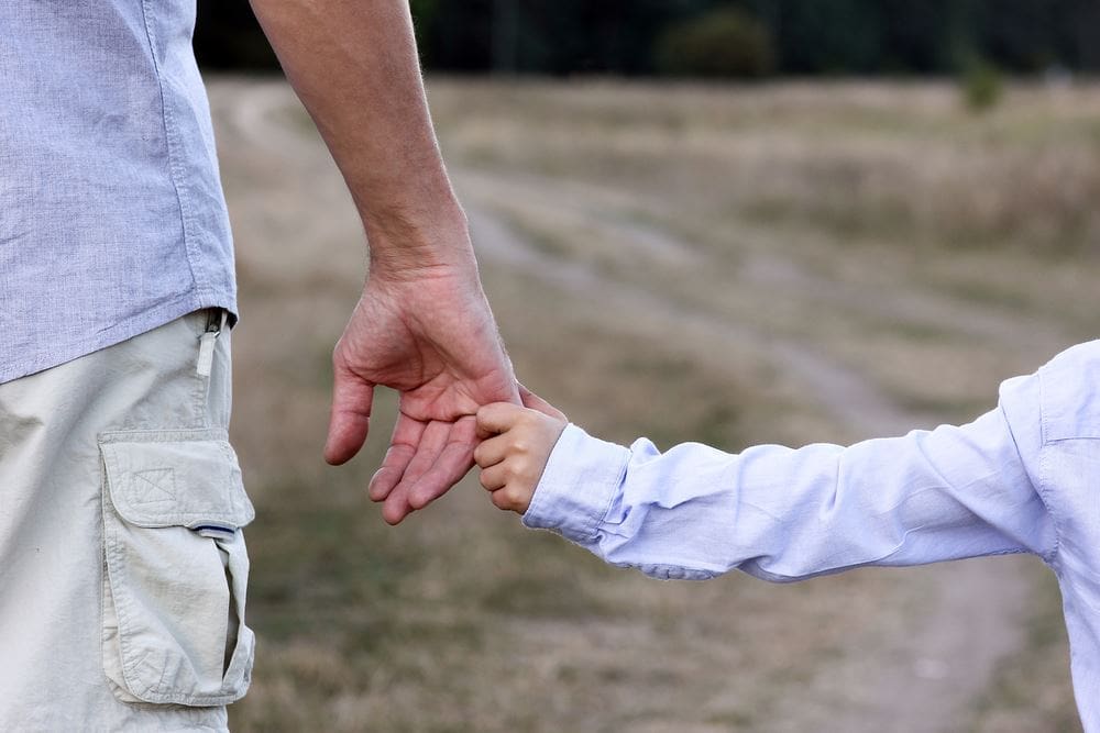 A man and woman holding hands in the dirt.