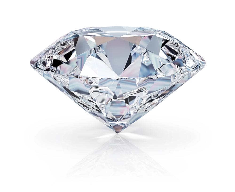 A diamond is sitting on the ground with its reflection.