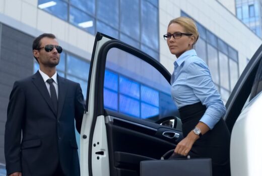 Female Executive exiting vehicle with guard opening door
